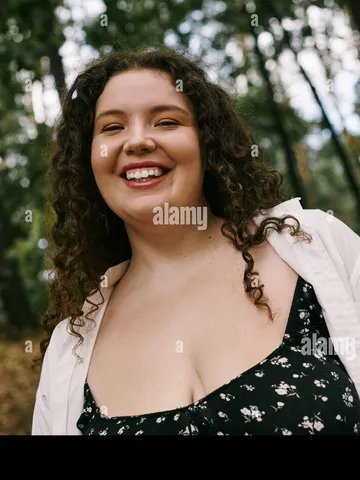 a cheerful plus size woman with curly hair revels in the bea