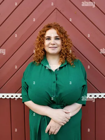 portrait plus size beautiful woman with curly red hair in gr