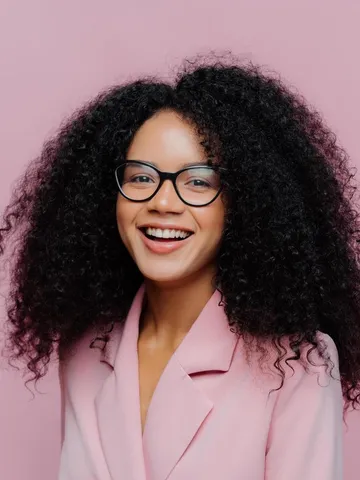 positive curly haired businesswoman wears spectacles formal