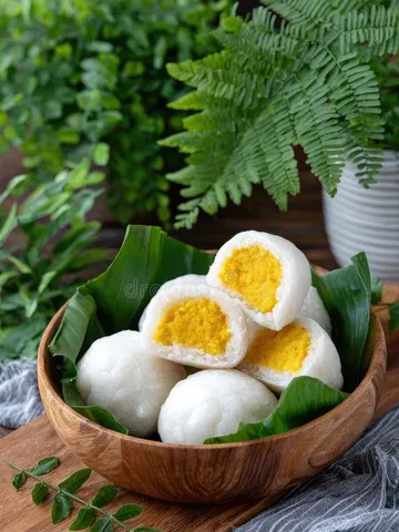 steamed white buns with yellow tops sit in a bowl on a dark